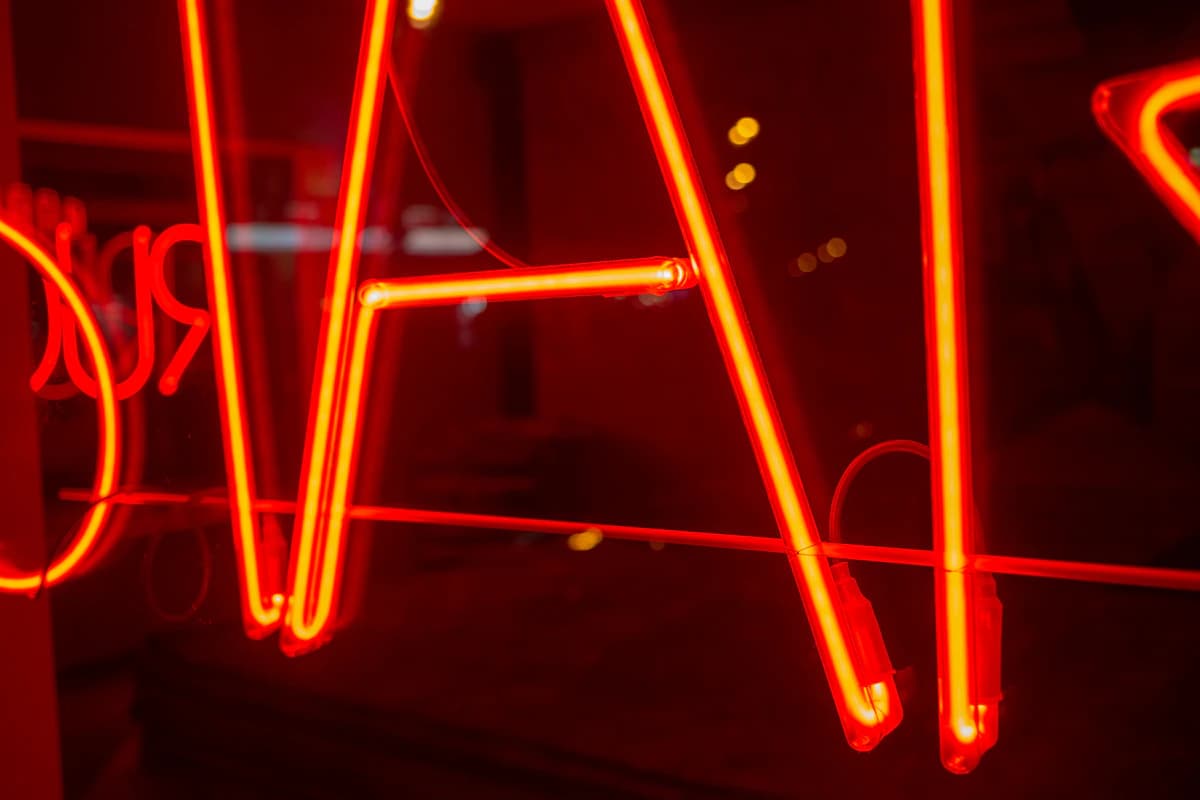 Neon tubes burning red behind the bar